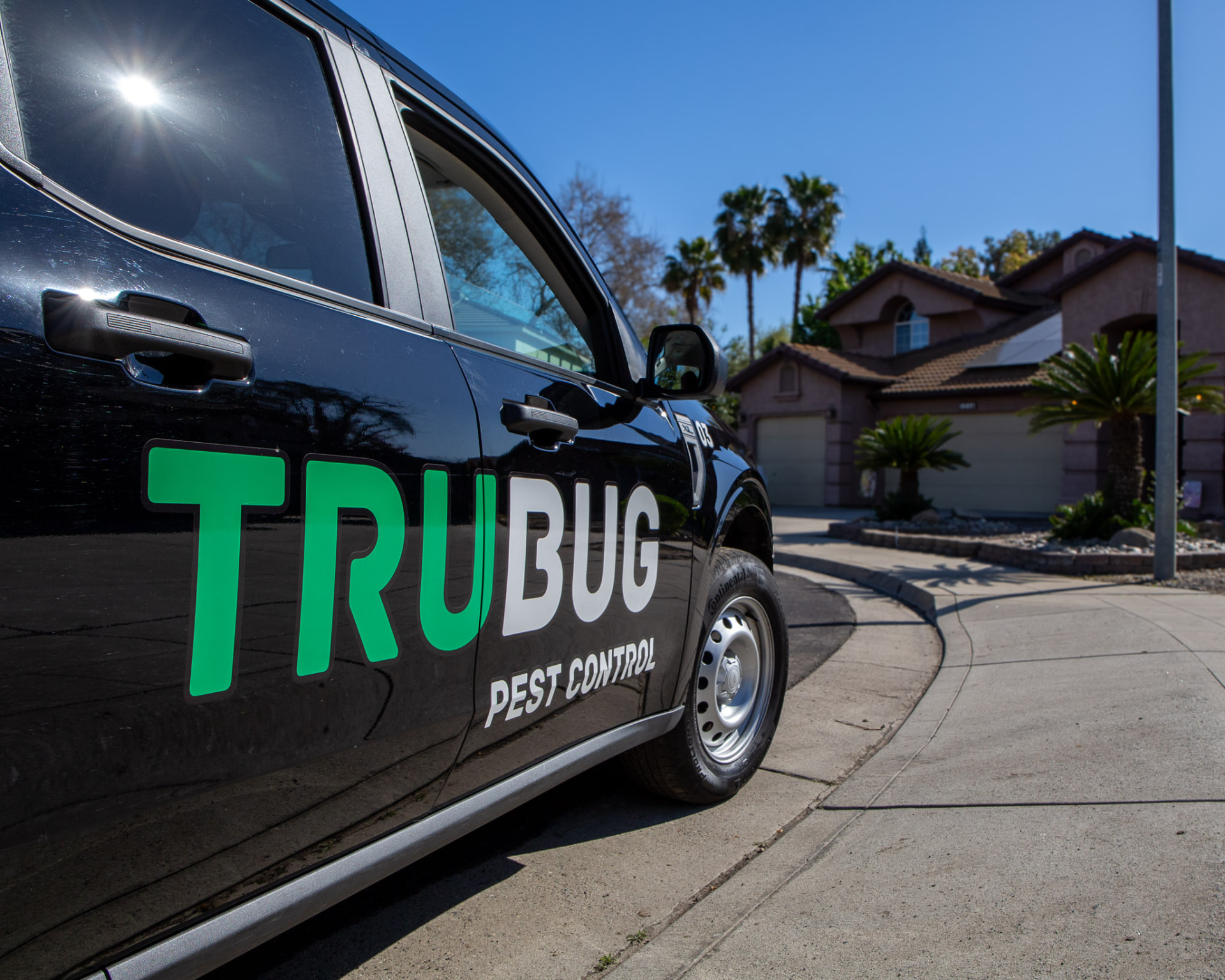 Black TruBug pest control truck in a Central Valley neighborhood