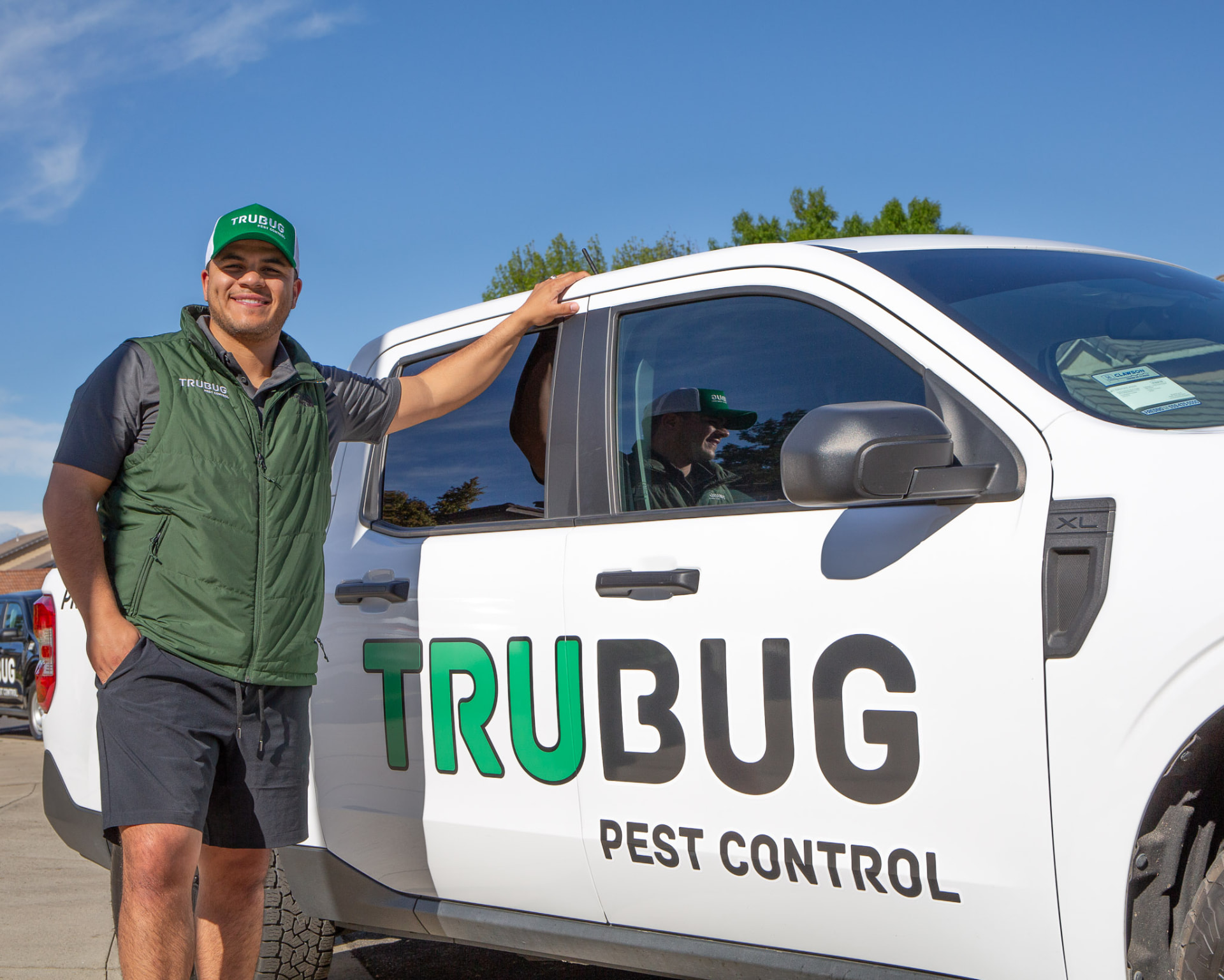 TruBug technician standing beside a branded service truck