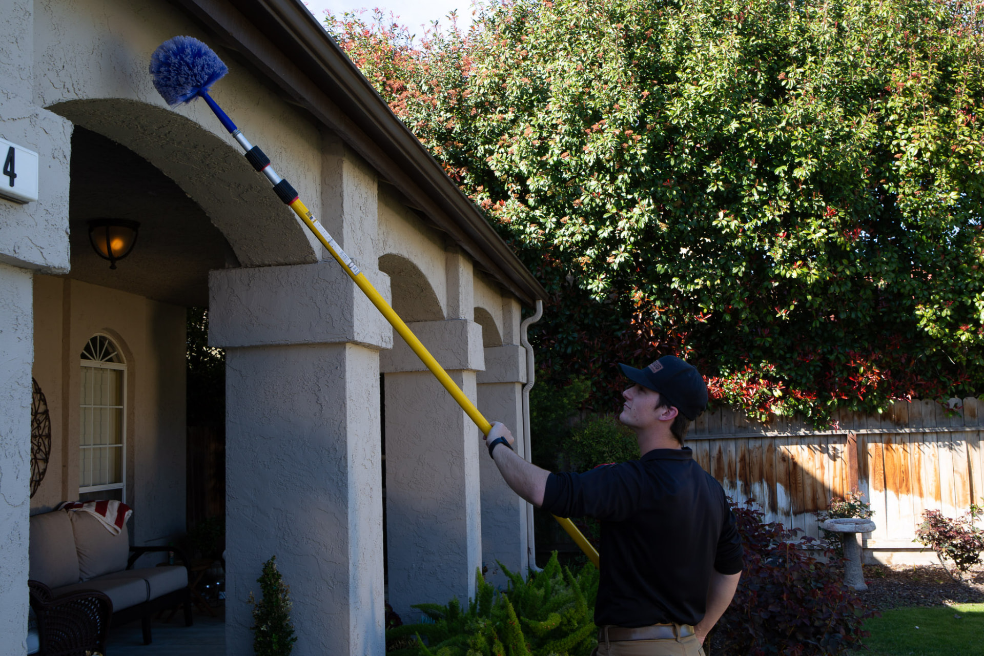 Technician de-webbing eaves with an extension duster