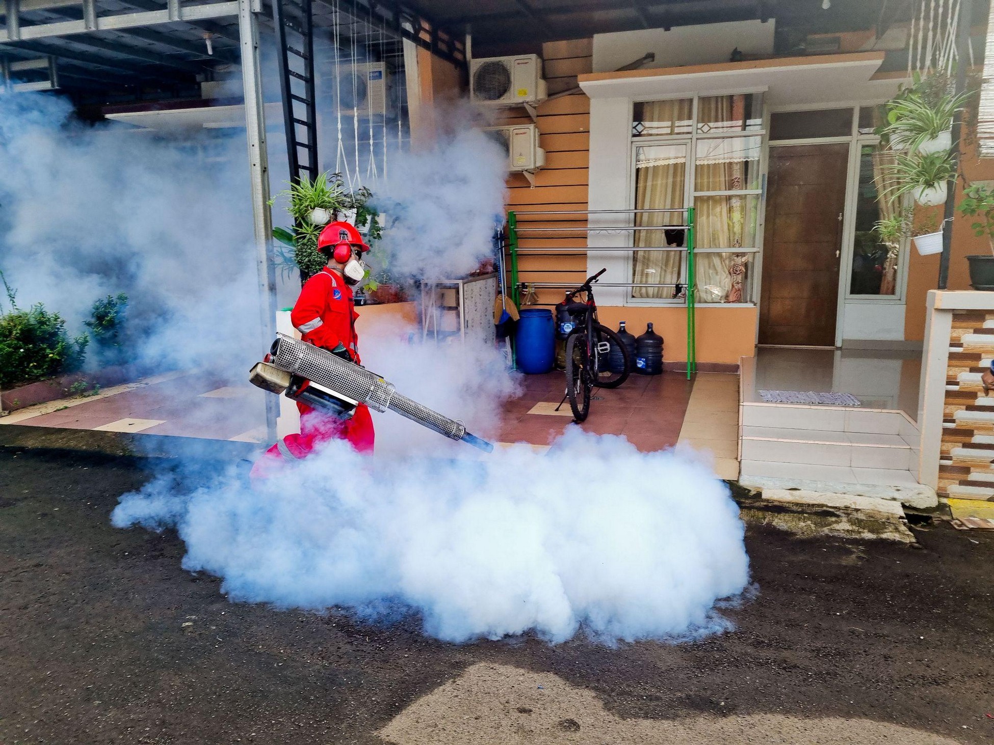 Pest control technician spraying near house